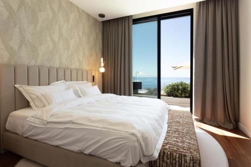 a bedroom with a large bed and a large window at Villa Anjos - Luxury Villa with Infinity Pool & Ocean View in Canhas