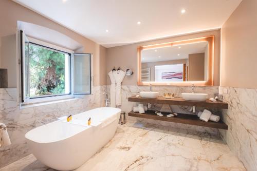 a bathroom with a tub and two sinks and a mirror at Hotel La Mandarine Saint Tropez in Saint-Tropez