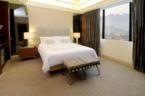 a bedroom with a large white bed and a large window at MS Milenium Monterrey Curio Collection by Hilton in Monterrey