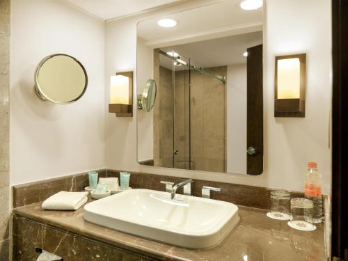 a bathroom with a sink and a mirror at MS Milenium Monterrey Curio Collection by Hilton in Monterrey