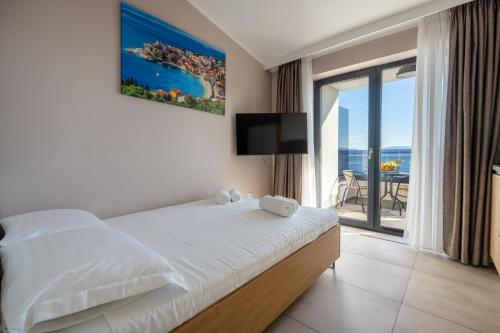 a bedroom with a bed and a balcony with a view at Wind Rose Bura-beachfront in Igrane