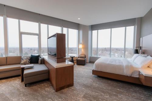 a bedroom with a bed and a couch and windows at Highpoint Hotel in Sioux Falls