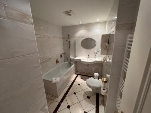 a bathroom with a toilet and a tub and a sink at Hotel garni SEESCHLÖSSCHEN in Kölpinsee