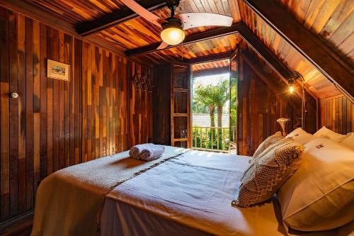 a bedroom with a large bed in a room with wooden walls at Rosa Chalé do Vô Walter in Gramado
