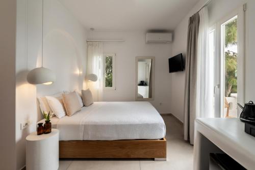 a white bedroom with a bed and a window at Galation in Mikonos