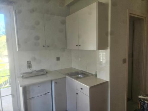 a kitchen with white cabinets and a sink at Fiore Hill Sea View Studios in Vasilikos