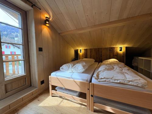 a bed in a wooden room with a window at Cosy duplex close to Verbier in Bruson