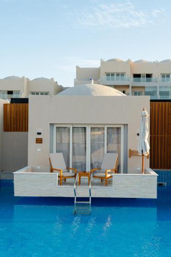 a swimming pool with two chairs and a house at Diamond Beach By Pearl Resort in Quseir