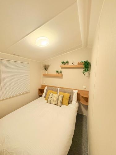 a bedroom with a white bed with two pillows at The Vacation Lyons Winkups Towyn in Kinmel Bay
