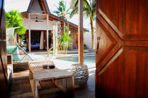 una puerta a una casa con una mesa y una piscina en Kaleydo Villas, en Gili Trawangan