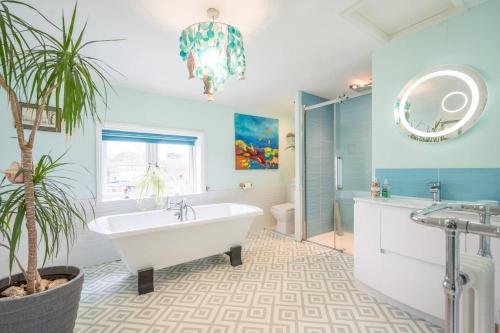 a bathroom with a white tub and a potted plant at The Old Bakery, Wrentham in Wrentham
