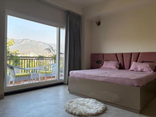 a bedroom with a bed and a balcony with a view at Golden Heights in Dehradun