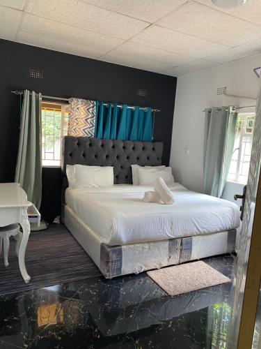 a bedroom with a large bed with blue curtains at Ramachi apartments in Livingstone