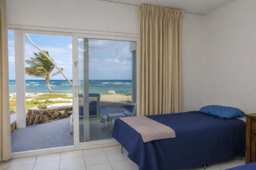 a bedroom with a bed and a view of the ocean at Palms Resort and Beach in La Grande Princesse