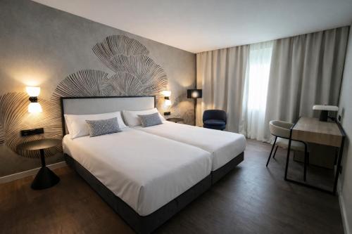 a hotel room with a large bed and a desk at URH Ciutat de Mataró in Mataró
