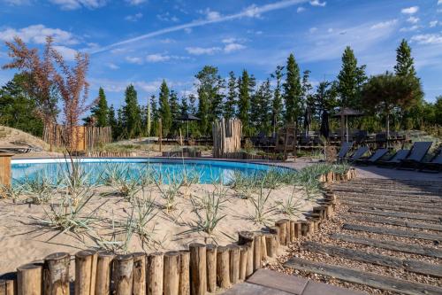 a swimming pool with chairs and a wooden fence at Waterstate Wellness hotel Goes in Goes