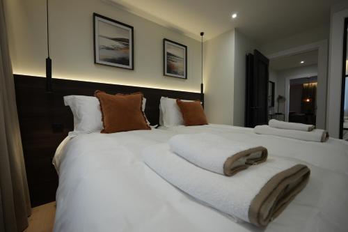 a bedroom with a large white bed with brown pillows at 1st Floor Luxury 2-Bed Apt Sleeps 6 in St. Andrews