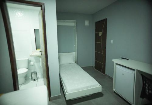 a small bathroom with a bed and a toilet at Pousada Recanto do Sol BF in Baía Formosa