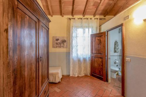 a bathroom with a toilet and a large wooden door at Podere Lamone a Monticchiello in Monticchiello
