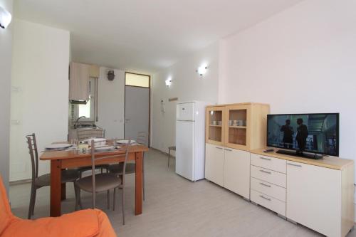 a kitchen and dining room with a table and a television at Appartamenti Eco del Mare in Lido di Pomposa