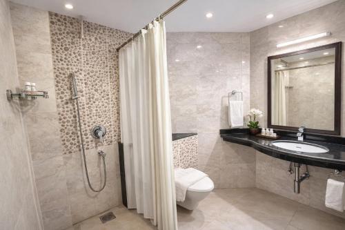 a bathroom with a shower and a toilet and a sink at Praia Da Oura Boutique Resort ,Goa in Majorda