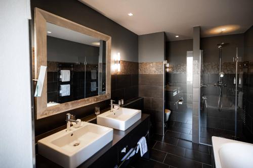 a bathroom with two sinks and a shower at Hotel Seepark Thun in Thun
