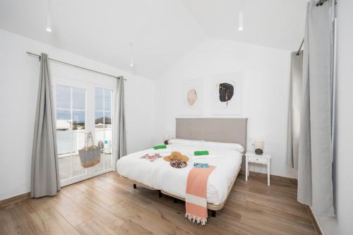 a white bedroom with a bed and a large window at Villa Yaiza Secret 2 in Yaiza