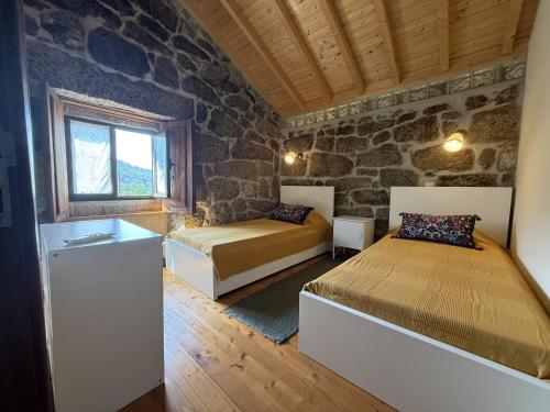 a bedroom with two beds and a stone wall at Serena Nest 01 in Rio Douro