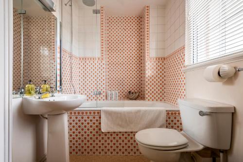 a bathroom with a toilet and a sink and a tub at West House in High Legh