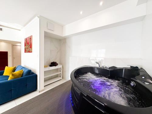 a black tub in a living room with a blue couch at Romantica SPA Kraków in Krakow