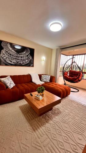 a living room with a red couch and a table at Midtown LakeView 2BR House with Heated pool, Netflix, 24Hr security & reception -Shawmut Nakuru in Nakuru