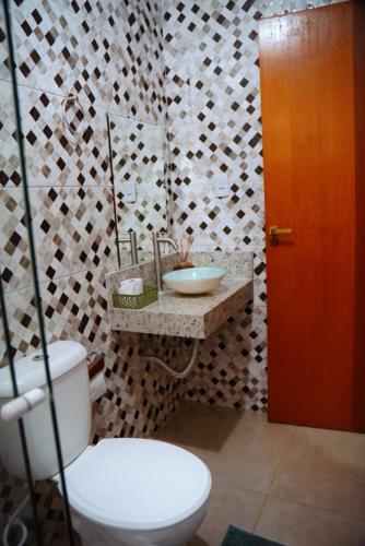 a bathroom with a toilet and a sink and a mirror at Village vila verde in Itaitu