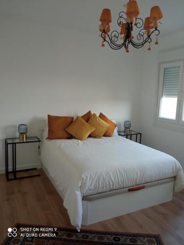 a bedroom with a white bed with orange pillows at A Muradana, Aldán in Pontevedra