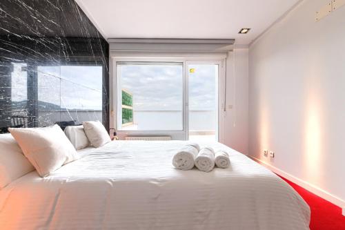 a bedroom with a large white bed with towels on it at Apartamento Bilbao Aeropuerto - Derio in Derio