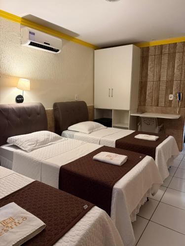 a hotel room with three beds and a kitchen at Hotel Estilo in Arapiraca