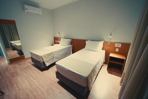 a hotel room with two beds and a mirror at Clatt Hotel in São João da Boa Vista