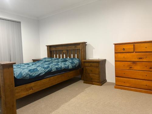 a bedroom with a wooden bed and a dresser at Beach House Shared in Alkimos