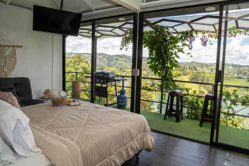 a bedroom with a bed and a large glass window at Rocks Glamping - Guatapé, El Peñol in El Peñol