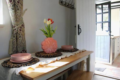 a table with plates and a vase with flowers on it at The Elm, Abbots Ripton in Abbots Ripton