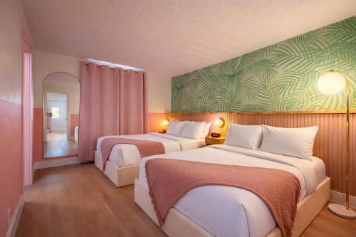 a hotel room with two beds and a green wall at Abode Beach House in Clearwater Beach