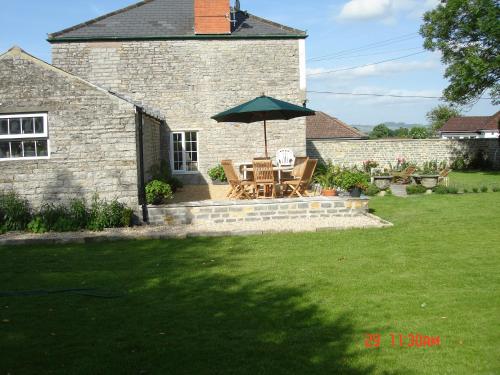 a patio with a table and an umbrella in a yard at Petercott in Shepton Mallet