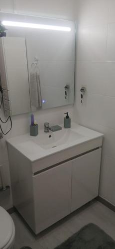 a white bathroom with a sink and a mirror at Casa da Gena in Nazaré