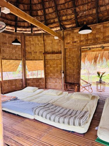 a large bed in a room with a wooden floor at Dhami Farmstay, Đông Giang, Đà Nẵng in Danang
