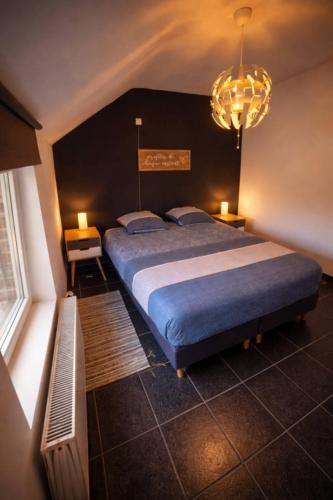 a bedroom with a large bed and a chandelier at Peace&Loft in Durbuy Old in Durbuy