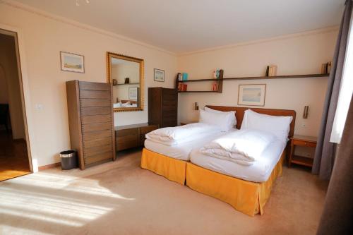 a bedroom with a bed with white sheets and a mirror at Chalet Miravalle 3 in Wengen