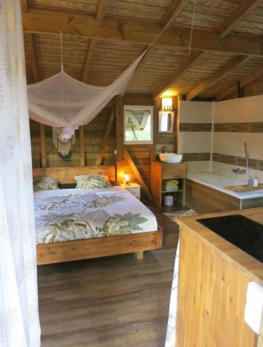 a bedroom with a bed and a sink and a tub at Cabane Autentikaz in Saint-François