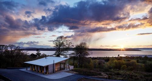 a small house on the shore of a lake at sunset at Kelburn Yurts - Fechan in Fairlie