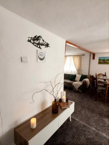 a living room with a table with a candle on a wall at BraziHouse - pine escape with jacuzzi in Petroşani