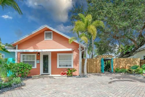 a orange house with a fence and palm trees at 2 Cottages Downtown Lake Worth - Private Pool in Lake Worth