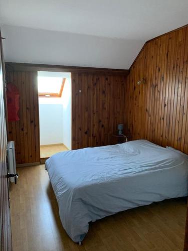 a bedroom with a bed with wooden walls and a window at Chalet Masana in Murat-le-Quaire